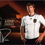Fußballspieler in einem weiß-schwarzen adidas-Trikot vor der Kulisse des Deutschland-Stadions mit Markenelementen und Unterschrift. Fritten, Fussball & Bier - www.soccer-warriors.de