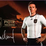 Ein Werbebild mit einem Fußballspieler in einem schwarz-weißen Adidas-Trikot mit dem Namen Piotr Trochowski und seiner Unterschrift darunter, vor dem Hintergrund eines Stadions und Adidas-Branding. Das Trikot Fritten, Fussball & Bier - www.soccer-warriors.de