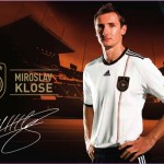 Fußballspieler posiert im Trikot der deutschen Nationalmannschaft mit einem Stadion im Hintergrund und Werbe-Branding-Elementen. Fritten, Fussball & Bier - www.soccer-warriors.de