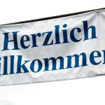 Ein Banner mit der deutschen Begrüßung „herzlich willkommen“ vor bewölktem Himmelshintergrund zur Feier eines Testspiels zwischen dem 1. FC Nürnberg und Racing Santander. Fritten, Fussball & Bier - www.soccer-warriors.de