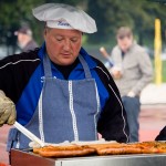 Mann grillt Würstchen bei einer Outdoor-Veranstaltung vor dem Testspiel des 1. FC Nürnberg. Fritten, Fussball & Bier - www.soccer-warriors.de