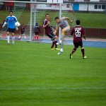 Ein Fußballspieler kickt den Ball während eines Testspiels, während andere auf dem Spielfeld zuschauen. Fritten, Fussball & Bier - www.soccer-warriors.de