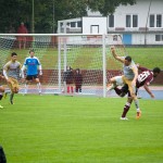 Spieler in einem Testspiel-Fußballspiel während eines Torversuchs, mit einem Spieler in der Luft, nachdem er den Ball getreten hat. Fritten, Fussball & Bier - www.soccer-warriors.de