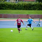Ein Fußballspieler in einem kastanienbraunen Trikot bereitet sich auf einen Schuss vor, während der Torwart während eines Testspiels zwischen dem 1. FC Nürnberg und Racing Santander vorrückt, um das Tor zu verteidigen. Fritten, Fussball & Bier - www.soccer-warriors.de
