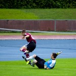 Ein Fußballspieler des 1. FC Nürnberg steht bei einem Tackling neben dem Torwart auf dem Spielfeld in der Luft. Fritten, Fussball & Bier - www.soccer-warriors.de
