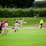Laufendes Amateur-Fußballspiel auf einer Wiese mit Spielern des 1. FC Nürnberg und Racing Santander, die sich auf den Ball konzentrieren. Fritten, Fussball & Bier - www.soccer-warriors.de