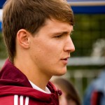 Ein junger Mann mit kurzen Haaren, der ein kastanienbraunes Sakko des 1. FC Nürnberg trägt, scheint mit konzentrierter Miene zur Seite zu blicken. Fritten, Fussball & Bier - www.soccer-warriors.de
