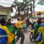 In Brasilien-Flaggen gehüllte Menschen nehmen an einer Straßenveranstaltung teil. Fritten, Fussball & Bier - www.soccer-warriors.de
